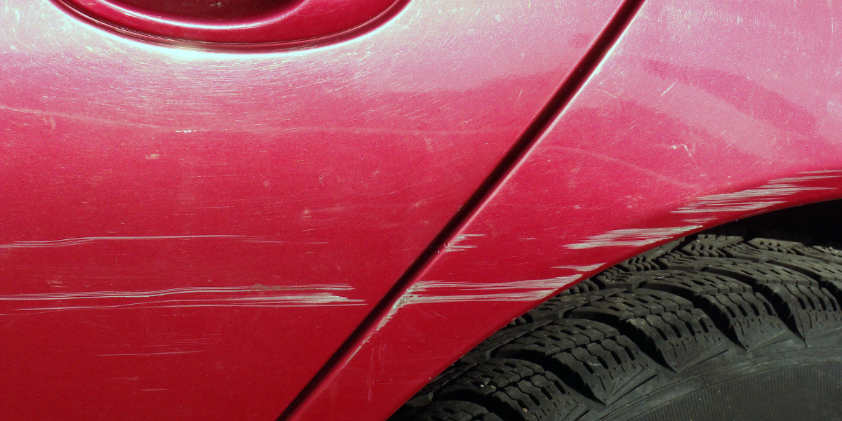 A red car shows a heavy scratch. To get this out an abrasive polish such as the ones mentioned in this blog would be required.
